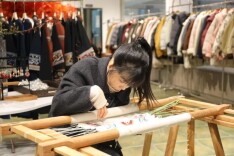 用蜷缩的双臂，她把民族服饰“绣”出海