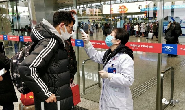 1月22日，长沙黄花国际机场，医护人员对旅客进行体温检测。谢霞 摄