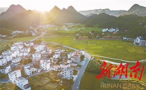 7月25日，宁远县九疑山瑶族乡，夕阳下的新居与远处的群山构成一幅美丽的乡村图画。湖南日报全媒体记者 李健 摄